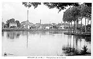 Perspective de la Seine"" : panorama sur la rive gauche, avec la pointe orientale de l'île Saint-Etienne sur le côté droit. La grande cheminée est celle de l'usine Vernin (aujourd'hui détruite). Carte postale. (BM Melun)
