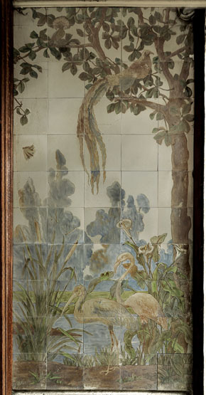 Vue d'ensemble du panneau à motifs animaux et végétaux ornant le porche d'entrée : couple d'échassiers (héron et flamand rose) dans un paysage de rivière ; au premier plan, arums et roseaux. Sur le côté, un arbre sur lequel sont posés deux oiseaux.