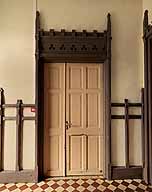 Vue de l'une des portes du palier au rez-de-chaussée. Le caractère néogothique de l'architecture de l'édifice est ici illustré par le traitement du linteau percé de motifs trilobés et surmonté d'un crénelage encadré de deux fleurons.